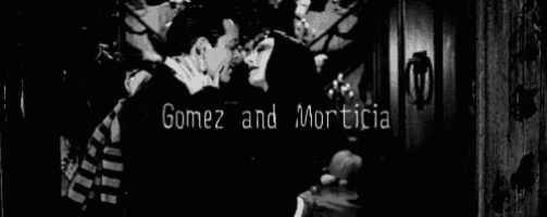 a black and white photo of a man and woman kissing in a hallway .