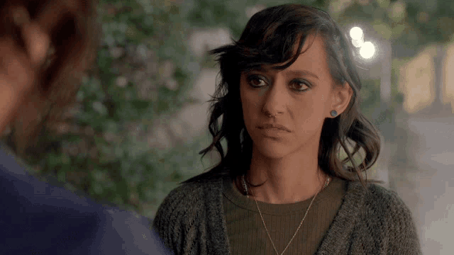 a woman with a nose ring and a necklace looks at a man