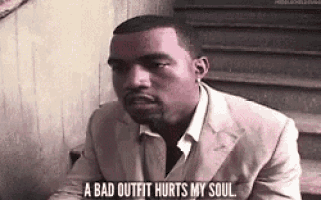 a man in a suit is sitting on a set of stairs and saying a bad outfit hurts my soul .