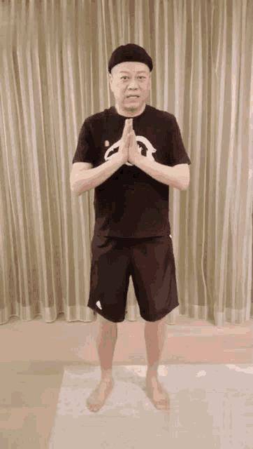 a man wearing a black shirt with the letter a on it is standing on a yoga mat