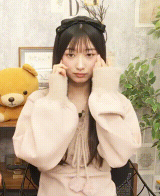 a girl wearing a headband and a white sweater is covering her ears with her hands .