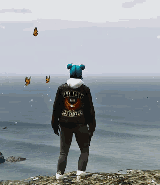 a person wearing a jacket that says the lost los santos stands in front of the ocean