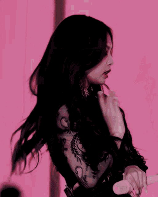 a woman in a black lace crop top is holding a gun