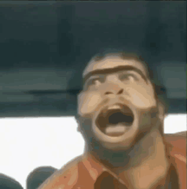a man with a beard is screaming with his mouth open in a car .