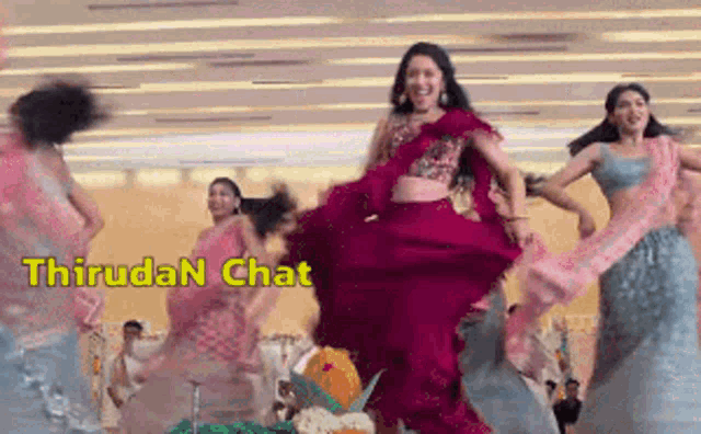 a group of women are dancing in front of a sign that says thiruda n chat .