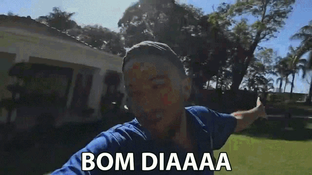 a man in a blue shirt says bom diaaaa in front of a white house