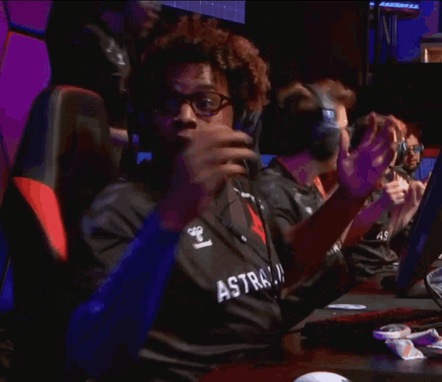 a man wearing a black astralis shirt is sitting at a computer