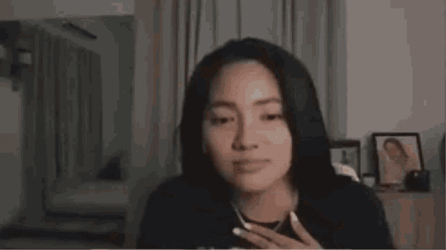 a young woman is sitting on a couch with her hands on her chin and smiling .