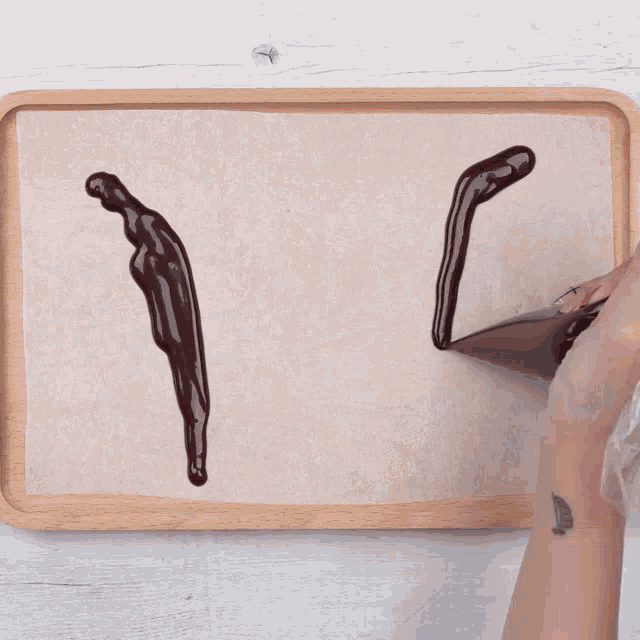 a person spreading chocolate on a piece of wax paper