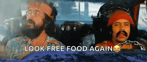 a man with a beard and mustache is driving a car with the words `` look free food again '' written on the screen .