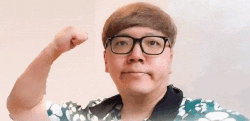 a man wearing glasses is flexing his muscles and making a face .