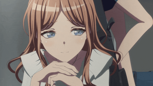 a girl with long brown hair and blue eyes has her hands folded