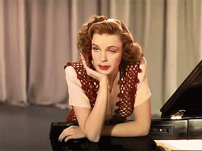 a woman leaning on a piano with her hand on her chin