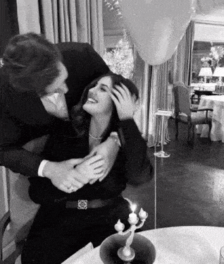 a black and white photo of a man hugging a woman who is wearing a loewe belt