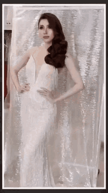 a woman in a white dress with fringe is standing in front of a white curtain