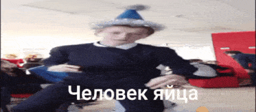 a boy wearing a party hat is dancing in a room with russian writing on the bottom