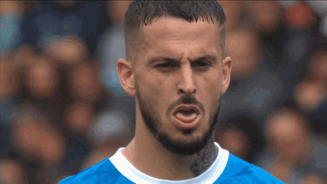 a man with a beard is wearing a blue shirt and making a face