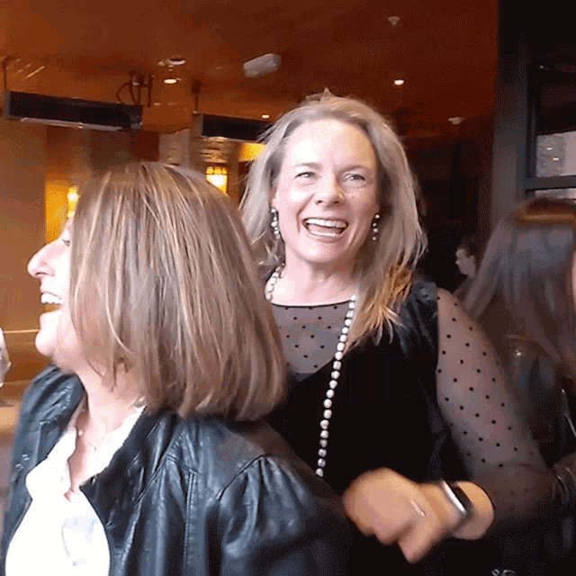 a woman wearing a black jacket and a polka dot top laughs