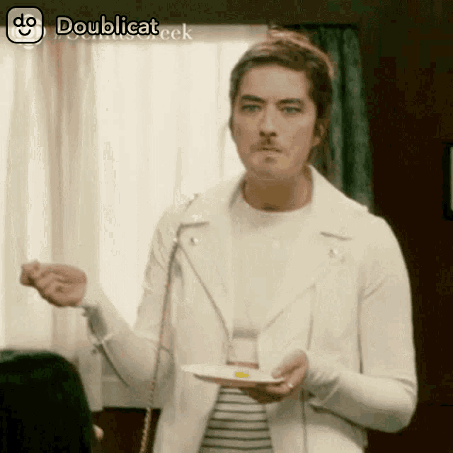 a man in a white jacket is holding a plate with a yellow item on it ..