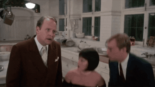 a man in a suit and tie is talking to a woman in a black dress