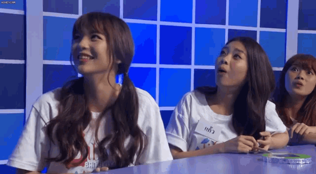 a group of girls are sitting at a table and one of them has a name tag that says ' a ' on it .
