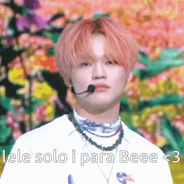 a young man with pink hair is wearing a microphone and a necklace ..