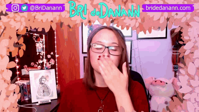 a woman wearing glasses covering her mouth with her hand in front of a sign that says bri danann