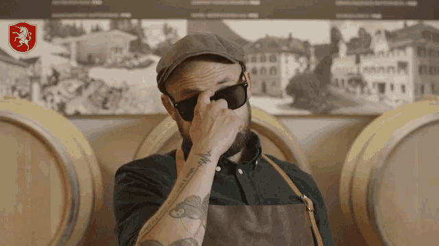 a man with a tattoo on his arm is wearing sunglasses and a hat