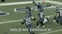 a group of football players running on a field with the words `` hold my dick '' .