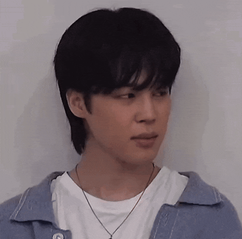 a young man wearing a blue jacket and a white t-shirt is looking at the camera .