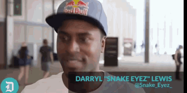 a man wearing a red bull hat is smiling
