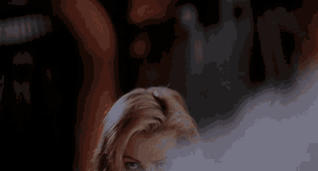 a woman is smoking a cigarette and covering her face with smoke coming out of her mouth .