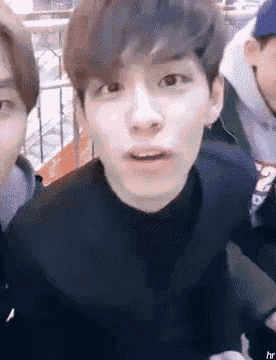 a group of young men are sitting next to each other and one of them is wearing a black turtleneck sweater .