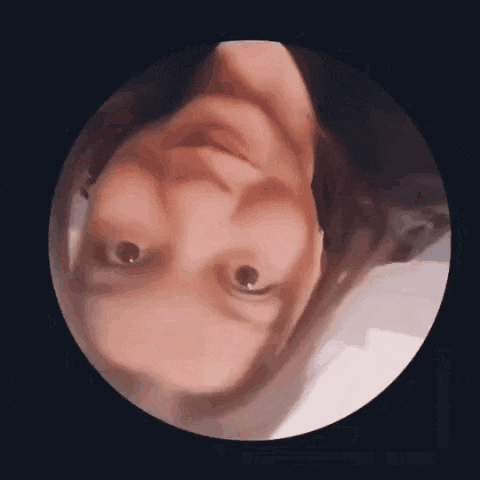 a close up of a person 's face in a circle with their head upside down .