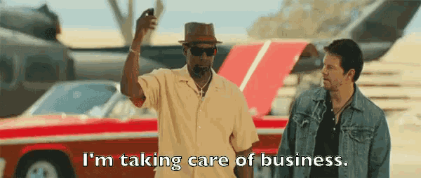 two men are standing next to a red car and one of them is saying i 'm taking care of business .