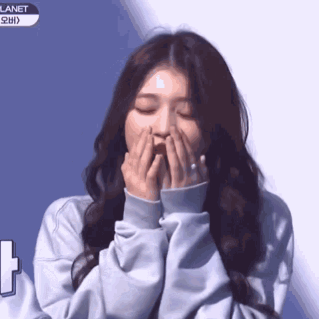 a woman covering her mouth with her hands in front of a screen that says planet
