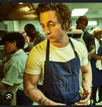 a man in a blue apron is standing in a kitchen