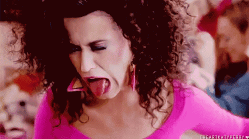a woman in a pink shirt is sticking her tongue out .