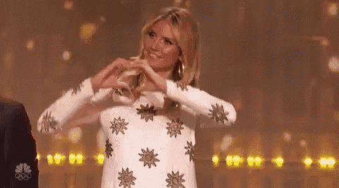 a woman in a white dress is making a heart with her hands .