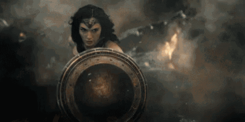 wonder woman is holding a shield in front of a smokey background .