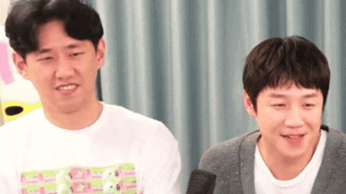 two men are sitting next to each other in front of a microphone .