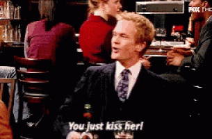a man in a suit and tie says " you just kiss her " while holding a glass of beer
