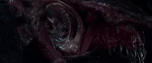 a close up of a monster 's mouth and ear in a dark room in a movie .