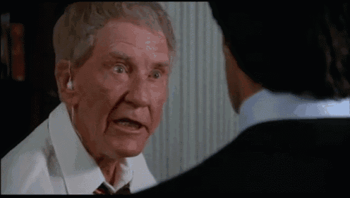 an older man wearing ear buds is talking to another man