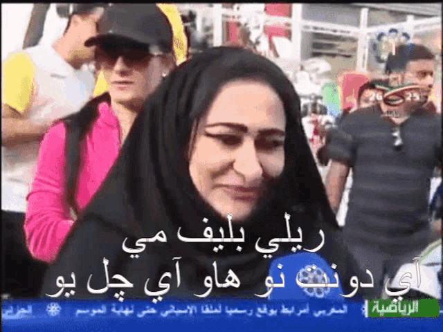 a woman wearing a hijab is being interviewed by a news reporter