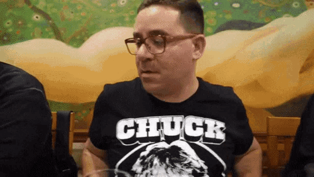 a man wearing glasses and a black chuck shirt
