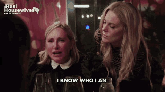 two women sitting at a table with the words i know who i am on the screen