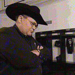 a man wearing a cowboy hat and glasses is looking down