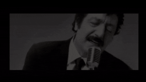 a black and white photo of a man singing in a microphone with the words sah written above him