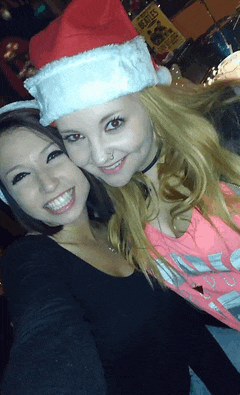 a woman wearing a santa hat stands next to another woman
